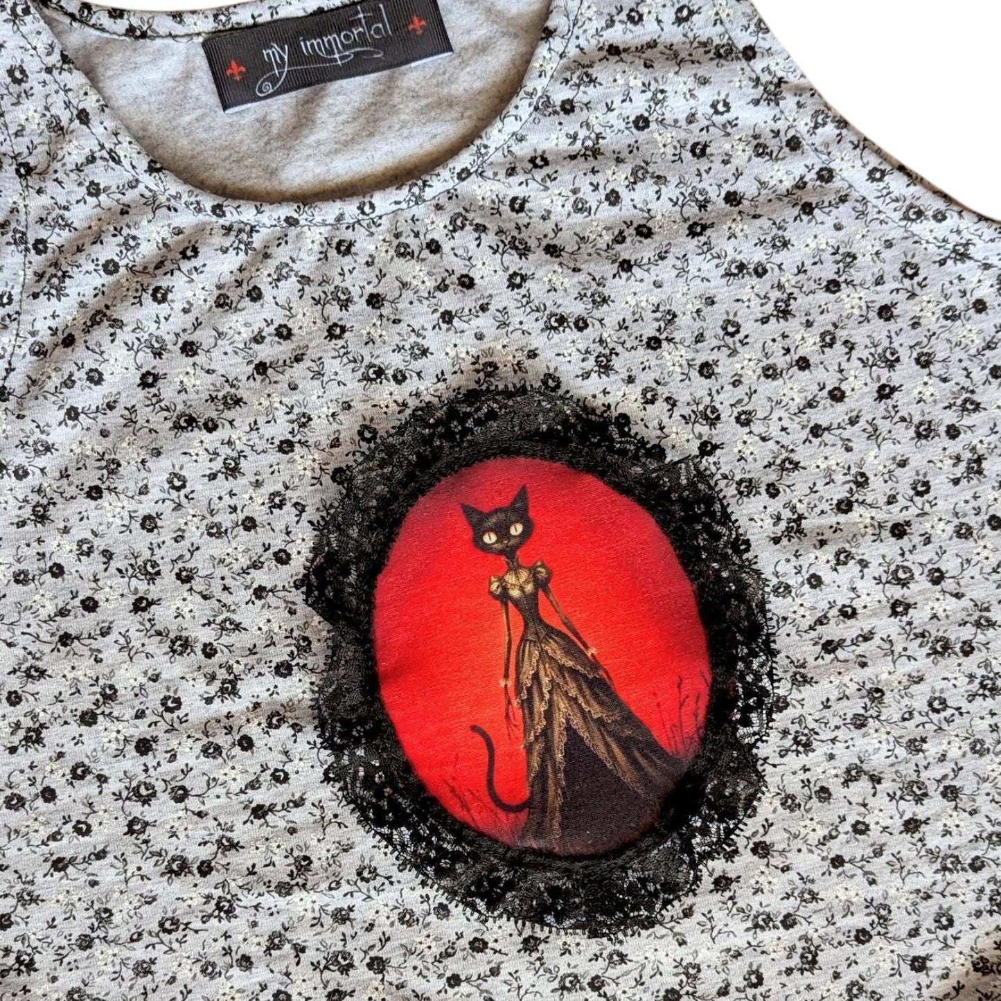 Camiseta gata, falda negra con picos y collar Flores de Lis
