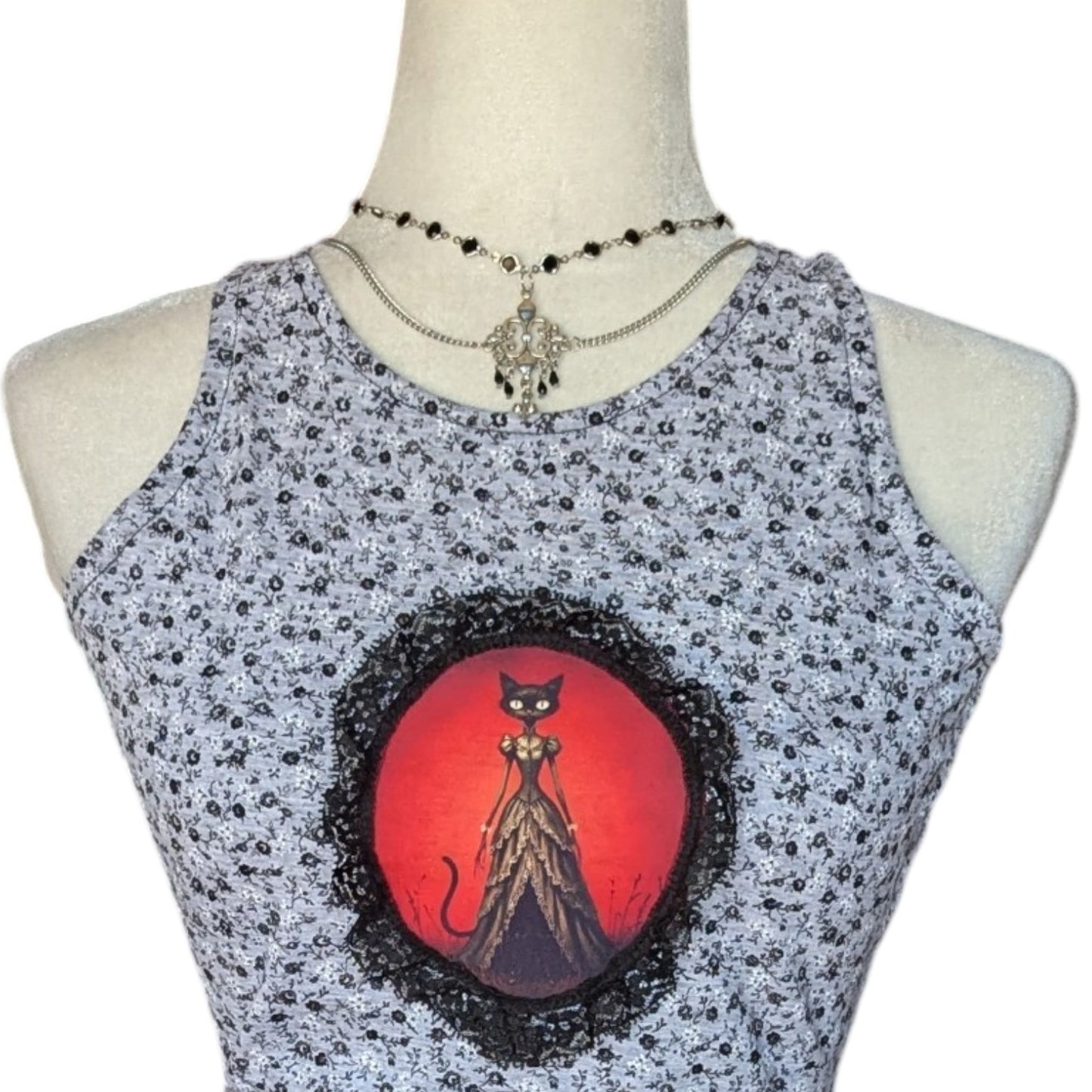 Camiseta gata, falda negra con picos y collar Flores de Lis
